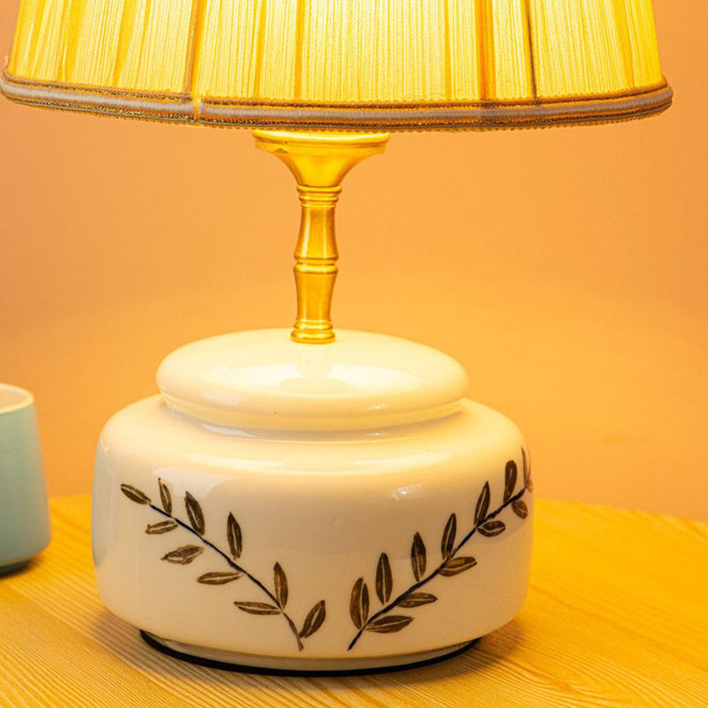 Lampe de table à 1 lumière avec abat-jour en tissu plissé trapézoïdal contemporain et base en céramique ronde pour chambre 